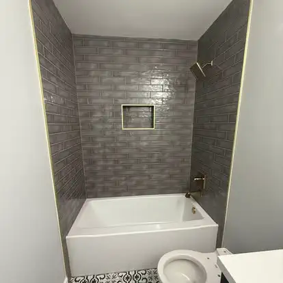 A bathroom with a gray tiled shower and a new tub