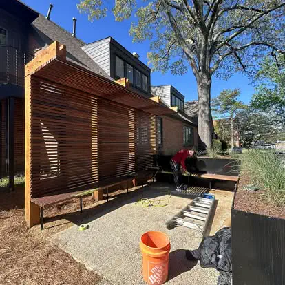 A slatted wood privacy screen with a canopy and built in bench at a commercial property