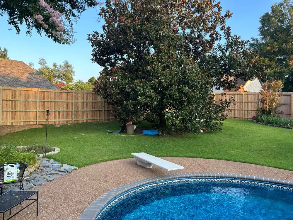 A backyard pool closed in by a tall wood privacy fence