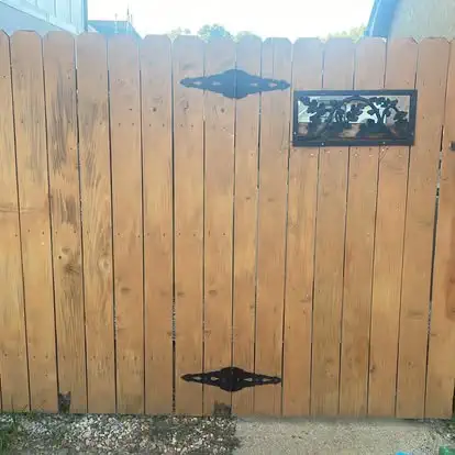 A wood privacy gate with a cast iron grill window