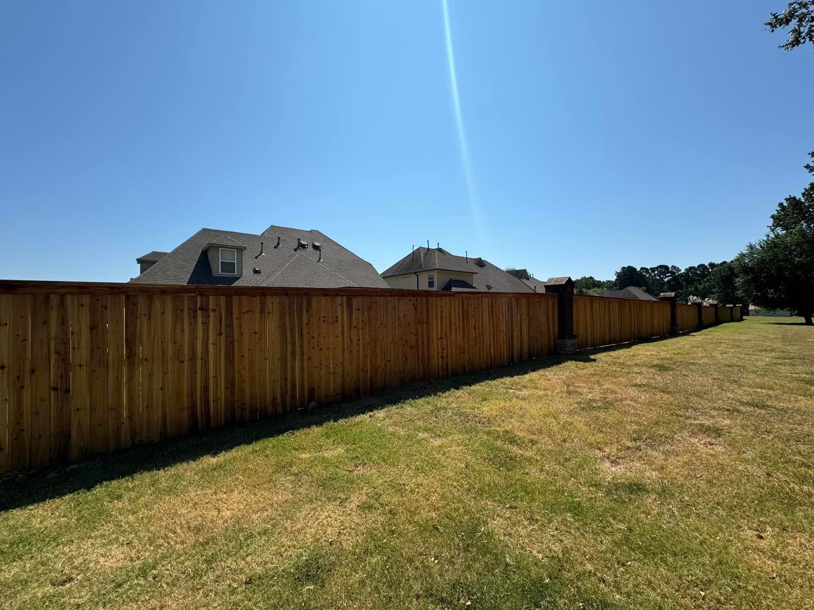 A long stained cedar privacy fence running along a backyard